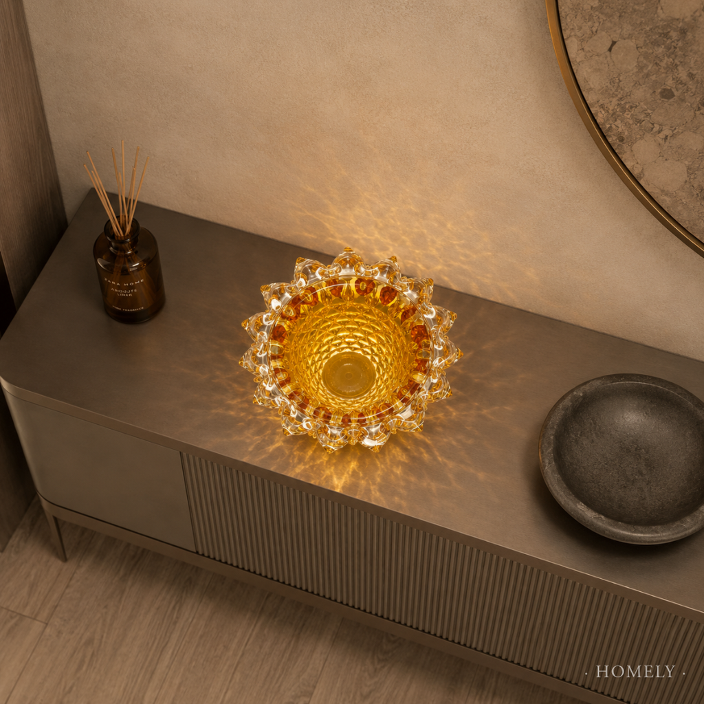 Decorative glass bowl on a wooden surface with a warm glow, surrounded by a bottle and a dark dish.