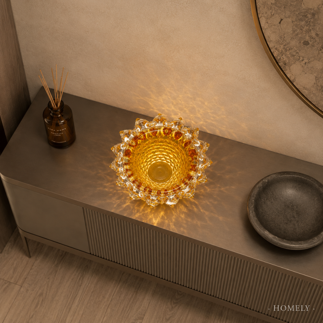 Decorative glass bowl on a wooden surface with a warm glow, surrounded by a bottle and a dark dish.