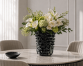 Floral arrangement in a black vase on a marble table with a neutral background