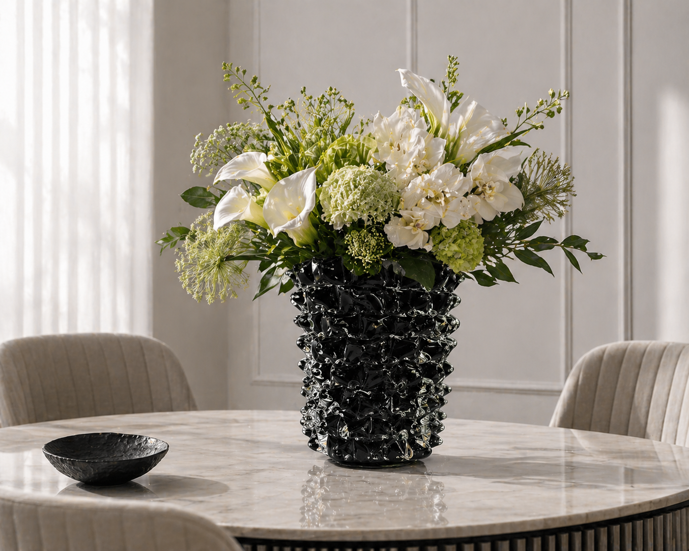 Floral arrangement in a black vase on a marble table with a neutral background