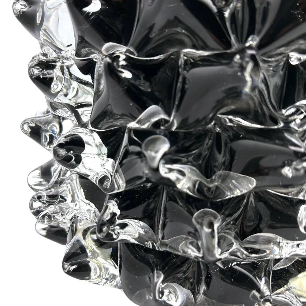 Close-up of a black and clear glass decorative item with swirling patterns