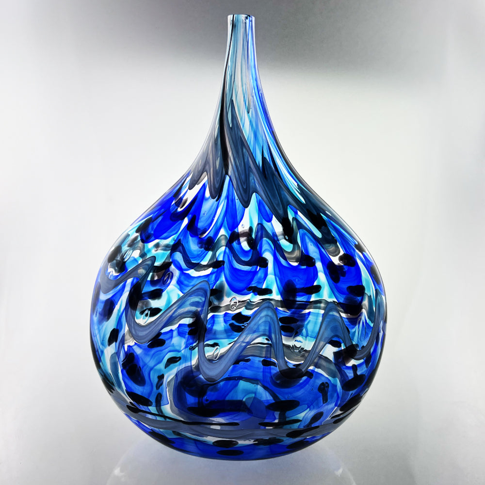 Blue glass vase with flame-like patterns on a gray background