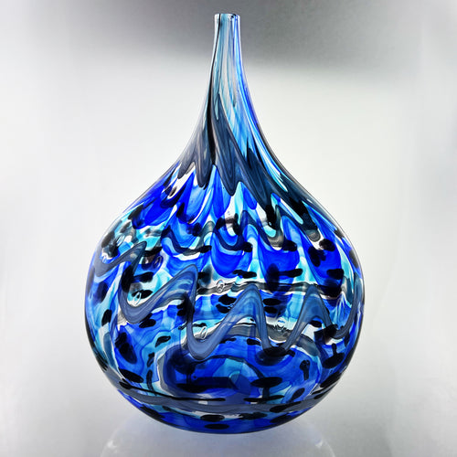 Blue glass vase with flame-like patterns on a gray background