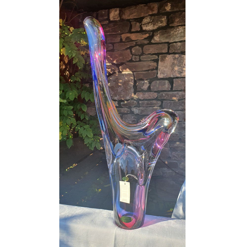 Colorful glass pipe on a white surface with a stone wall background