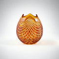 Decorative amber glass vase with textured pattern on a white background