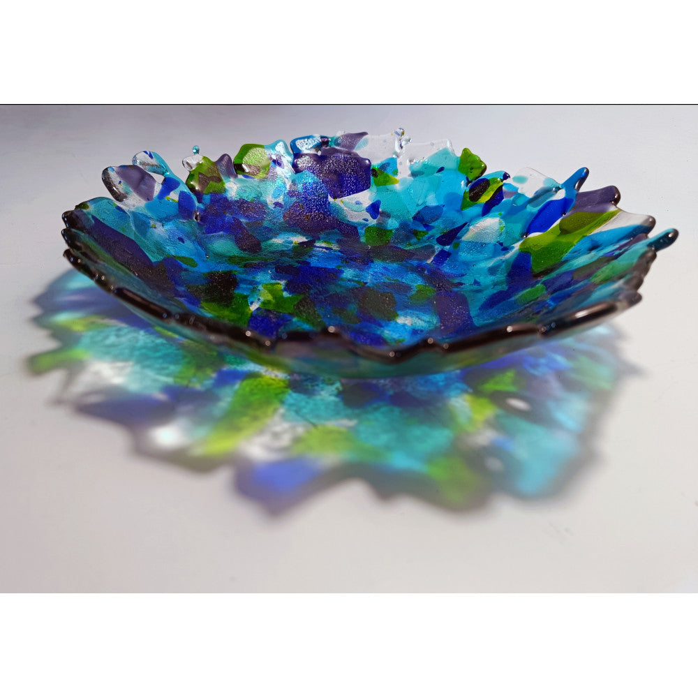 Decorative glass bowl with blue and green patterns on a white background