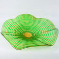Green glass bowl with wavy design on a white background