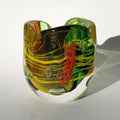 Colorful glass vase with green, yellow, and red swirls on a white background