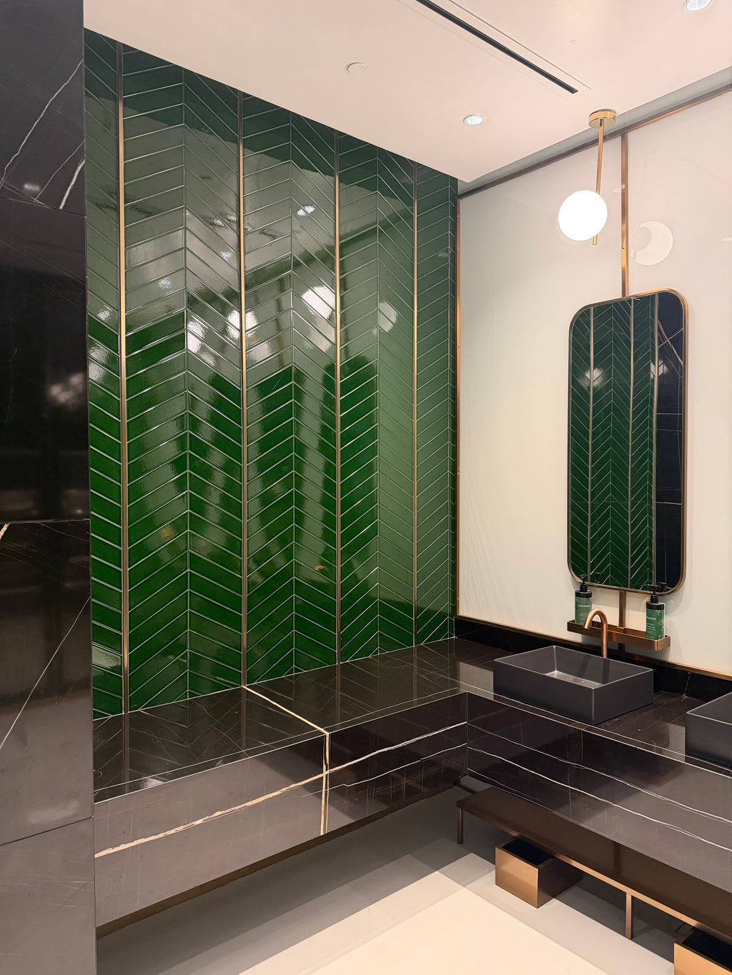 Modern bathroom with green tiled floor and wall-mounted mirror.