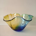 Glass bowl with wavy design in yellow, green, and blue on a white background