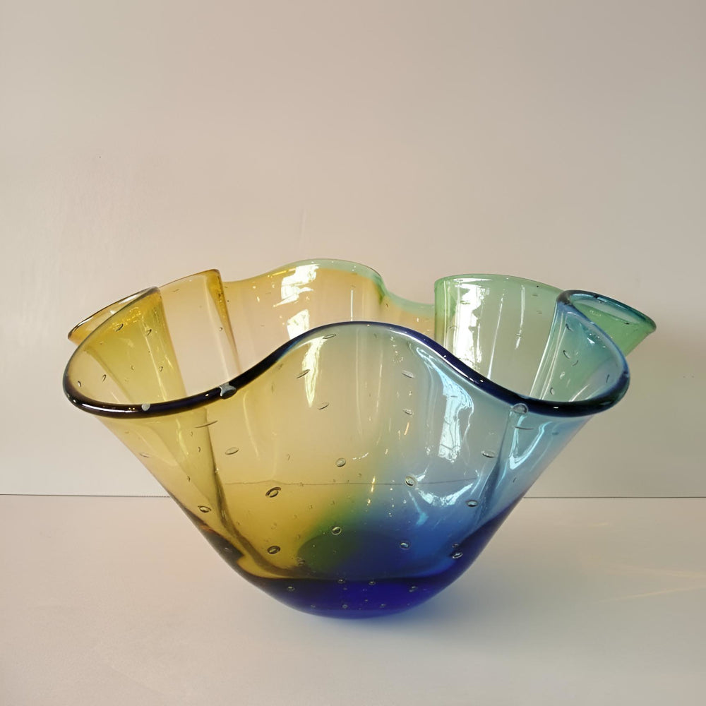 Glass bowl with wavy design in yellow, green, and blue on a white background