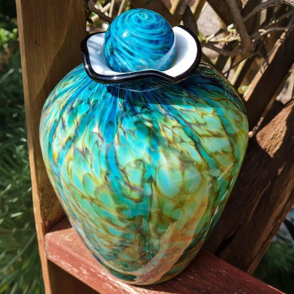 Glass urn with blue and green swirl design on a wooden surface