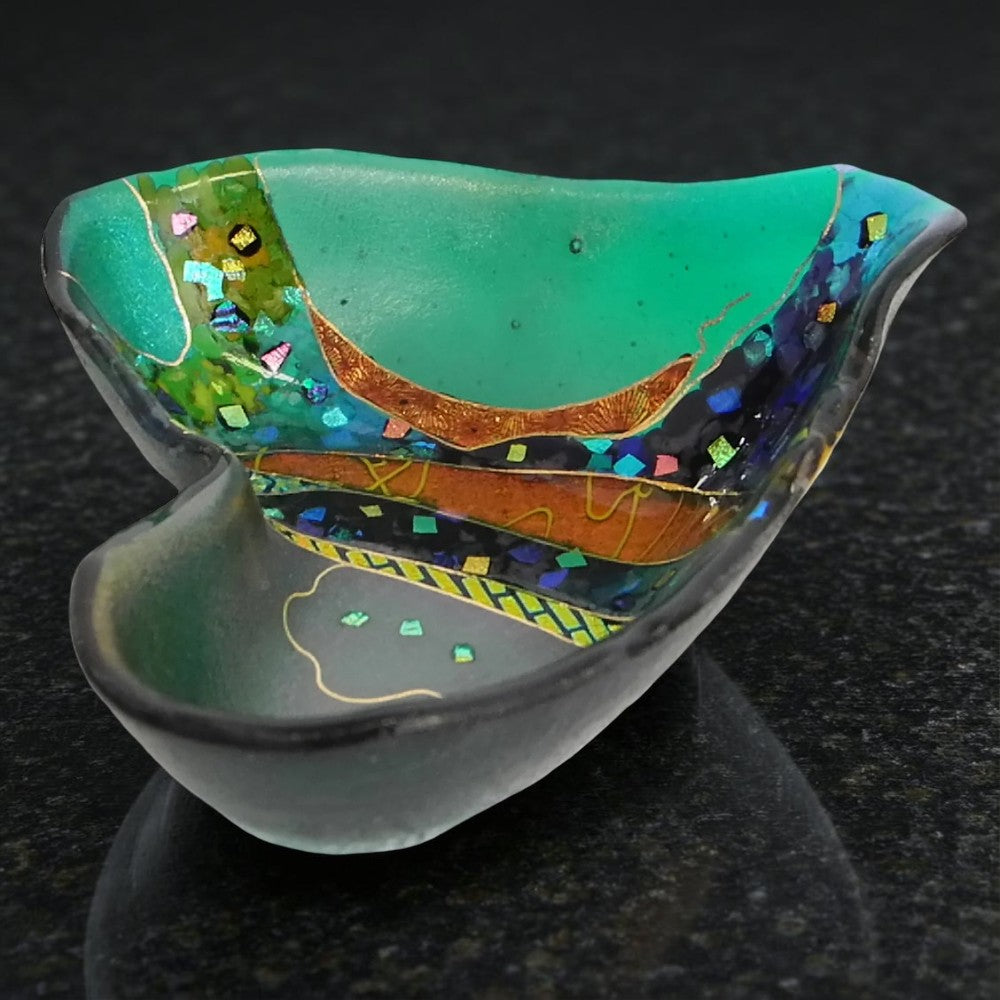 Decorative glass bowl with colorful patterns on a dark background