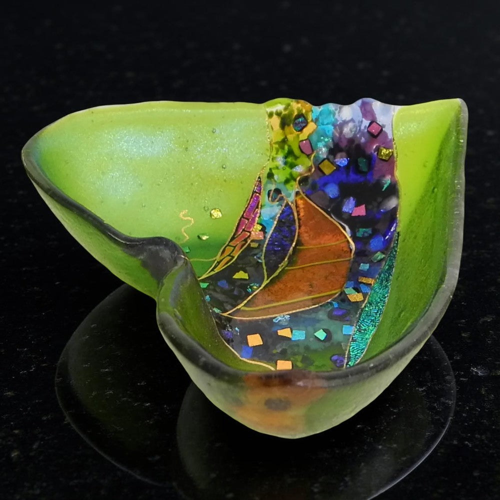 Colorful glass sculpture with leaf design on a black background