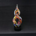 Multicolored glass sculpture on a black stand against a black background
