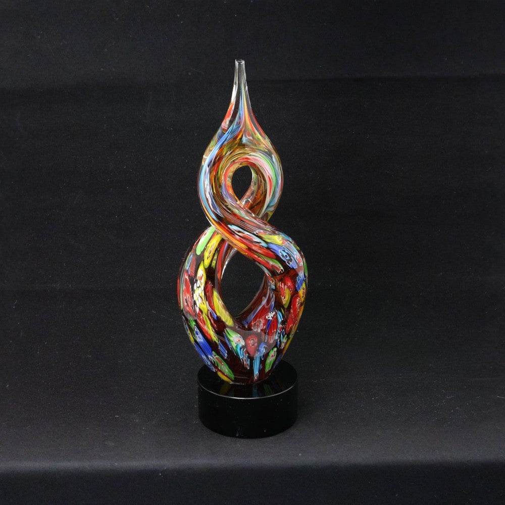 Multicolored glass sculpture on a black stand against a black background