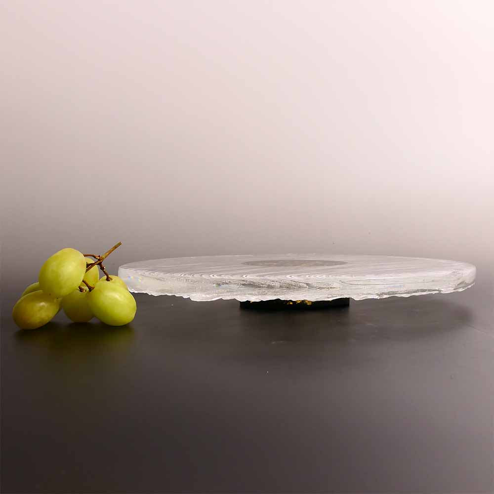 Clear stone platter with a bunch of grapes on a gray background